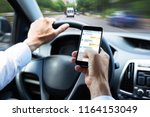 Close-up Of A Man's Hand Typing Text Message On Mobile Phone While Driving Car