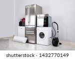 Set Of Household Kitchen Electronics Appliances On Reflective White Floor Against Wall