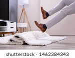 Small photo of Low Section Of Man Legs Stumbling With A Carpet In The Living Room At Home