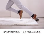 Small photo of Low Section Of Man Legs Stumbling With A Carpet At Home