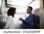 Young African Businesspeople Having Conversation In Elevator