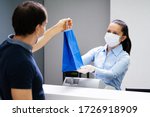 Small photo of Cashier In Retail Shop Or Store At Counter Wearing Face Mask