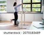 Worker Stretch Exercise At Stand Desk In Office