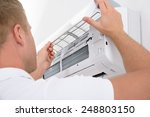 Portrait Of A Young Man Adjusting Air Conditioning System