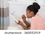 Smiling Young African Woman Checking Schedule In Diary