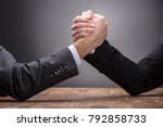 Close-up Of Two Businesspeople Competing In Arm Wrestling On Grey Background