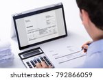 stock-photo-close-up-of-businessman-calculating-the-invoice-using-hybrid-laptop-and-calculator-at-workplace-792866059.jpg