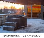 Hot outdoor wooden bath tub  on terrace of private house at winter. Luxury cottage. Finnish sauna.