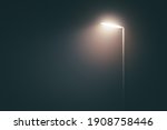 Streetlight post with bright light in a misty fog in the evening in a dramatic mood