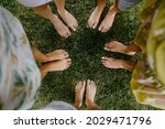 Barefoot female feet on green grass, standing in a circle. Top view.