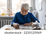 Small photo of Elderly woman filling out financial statements