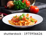 Small photo of Classic italian pasta penne alla arrabiata with basil and freshly grated parmesan cheese on dark table. Penne pasta with chili sauce arrabbiata.