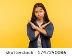 No way, this is finish! Portrait of dissatisfied girl in denim shirt gesturing stop, x sign with crossed hands, way prohibited, warning of troubles. indoor studio shot isolated on yellow background