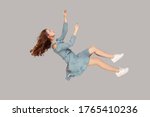 Small photo of Hovering in air. Relaxed beautiful girl ruffle dress and curly soaring hair levitating, flying in dream with hands up, reaching for something high. indoor studio shot isolated on gray background