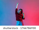 I am champion! Neon light portrait of victorious delighted happy brunette woman raising hands, shouting for joy, screaming celebrating win success, thrilled emotions. indoor studio shot isolated