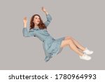 Small photo of Hovering in air. Full length beautiful pensive girl in vintage ruffle dress levitating flying in mid-air, looking up with dreamy relaxed expression. indoor studio shot isolated on gray background