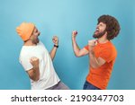 Portrait of two young adult hipster men showing yes gesture and screaming celebrating victory, success, dreams comes true, euphoria. Indoor studio shot isolated on blue background.