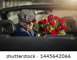 Small photo of Sugar Daddy Eyes Seduction. Attractive Caucasian Men with Roses Awaiting His Girlfriend While Seating in a Convertible Car.