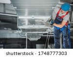 Industrial Theme. Warehouse Heating and Cooling System Installation by Professional Caucasian Technician. Commercial Building Ventilation Rectangle Canals. Air Distribution.