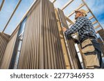 Caucasian General Construction Worker in His 40s Building Small Modern Garden Shed Using Wood and Composite Materials.
