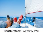 Pairs legs of man and woman legs in red and blue topsiders on white yacht deck. Yachting
