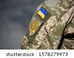 Ukrainian soldier wearing military uniform with flag and chevron depicting trident - Ukrainian emblem and national symbol