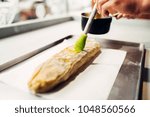Chef hand lubricates strudel with egg and butter
