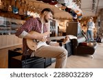 Man enjoying sound while playing guitar connected to amplifier