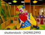 Small photo of Cute funny clown artist holding heart showing love and adoration