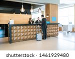 Businessman making booking at front desk with Latin receptionists in hotel lobby 
