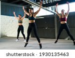 Active and healthy women doing jumping jacks during a HIIT class. Three beautiful and fit women working out at the gym with power training