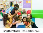 Small photo of Lovely beautiful preschool teacher hugging her kindergarten students and enjoying coming back to school