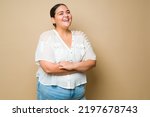 Excited plus size woman laughing and having fun feeling positive emotions in front of a studio background