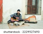 Small photo of Man beggar living in poverty playing the guitar to sing a song and ask for money on the street