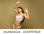 Excited mexican woman dancing and having fun in underwear in front of a studio background