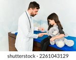 Small photo of Doctor doing a prick test or SPT testing for allergies on the skin arm of an adorable little girl with a teddy bear