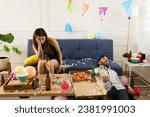 Small photo of Sick young woman with a headache and nausea looking hangover with an unconscious man after celebrating drinking during a birthday party