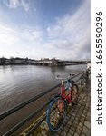 Small photo of MAASTRICHT, THE NETHERLANDS - MARCH 02 2020: Skyline of Maastricht with the medieval Servatius bridge over the river Meuse. Built from 1280 - 1298, Maastricht. A colored bike in foreground