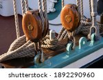 Small photo of Two brown wooden pulleys with ropes on the side of a ship. Focus on the wood of the pulley at the left