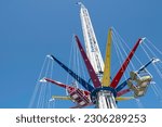 Small photo of Modern empty Swing ride, Wave Swinger or Mega whirligig at a funfair against a blue sky. The rotating top of the carousel also tilts for additional variations of motion