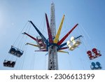 Small photo of Modern empty Swing ride, Wave Swinger or Mega whirligig at a funfair against a blue sky. The rotating top of the carousel also tilts for additional variations of motion
