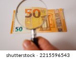 fifty euro banknote viewed with a magnifying glass