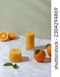 Small photo of fresh orange juice in a glass and decanter. Oranges on the table