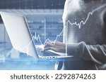 Close up of hacker hands using laptop with growing blue financial forex chart on blurry office interior background. Stock, economy, hacking, market and trade concept. Double exposure