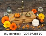 Small photo of Calendula flower preparation for natural skincare remedy with brass apothecary scales, ointment and oil bottles. Heals wounds, acne, eczema, stimulates collagen, is antiseptic and anti inflammatory.