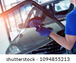 Automobile special workers replacing windscreen or windshield of a car in auto service station garage. Background