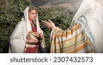 Small photo of 2 young human faith Lord hand ask god drink offer help jew maid slave look stare gossip hold old retro jar vase arab shawl cloth. Bless joy hope israeli rural lady chat preach face farm yard hous home