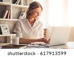 Beautiful business woman is using a laptop and smiling while working in office