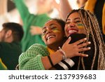 Brazilian young sisters football fans celebrating their team's victory at stadium.