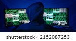 Small photo of Rear view od hooded hacker by computer in the dark room at night, cyberwar concept.